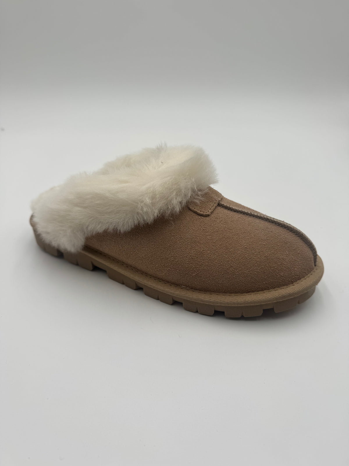 A single brown suede slipper with a fluffy white faux-fur trim, photographed on a light gray studio background.