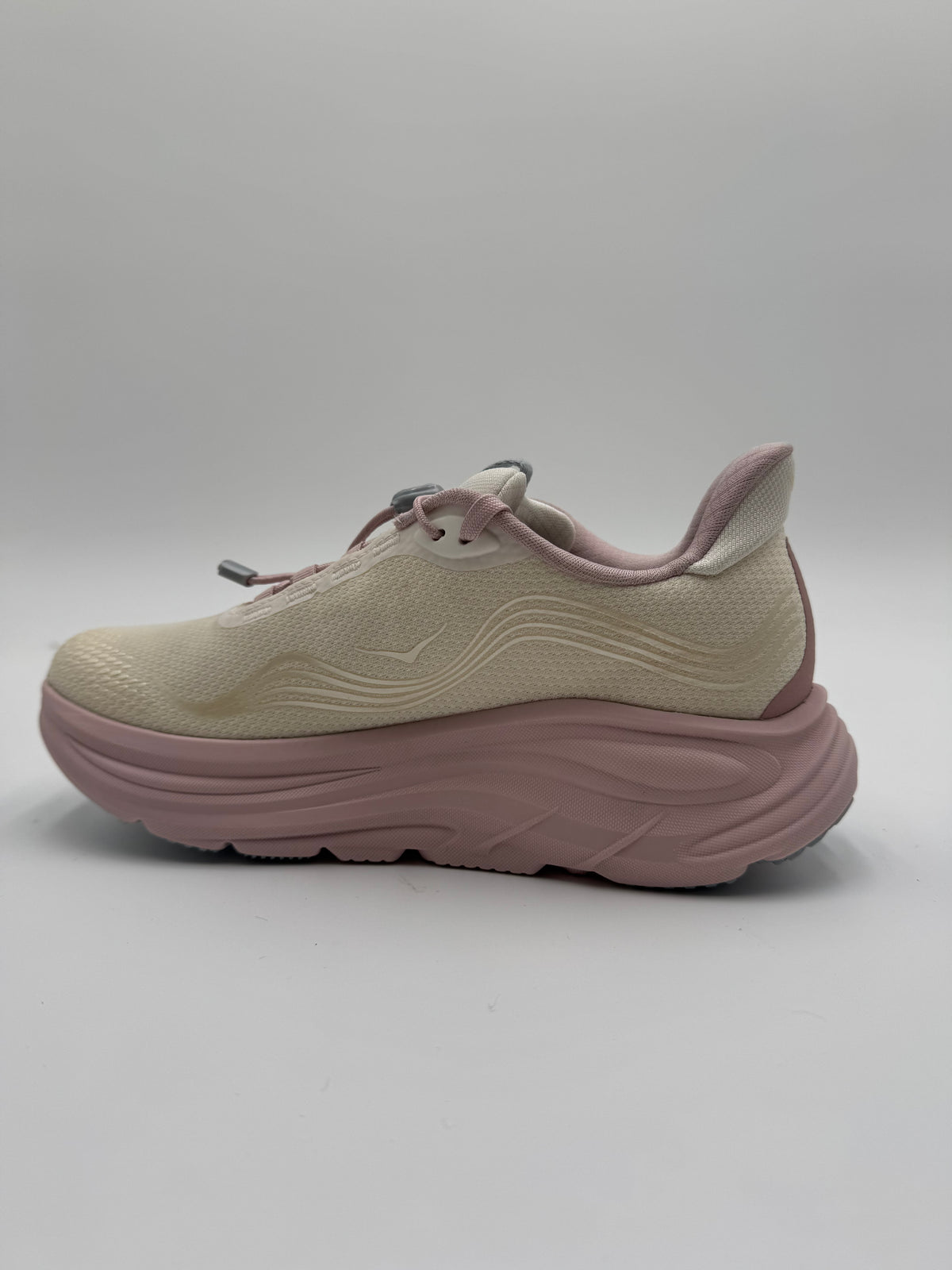 A single platform sneaker shown from the side profile against a neutral gray studio background. The shoe features a light beige textured mesh upper with wavy embossed detailing, a dusty pink thick platform sole, and matching dusty pink laces.