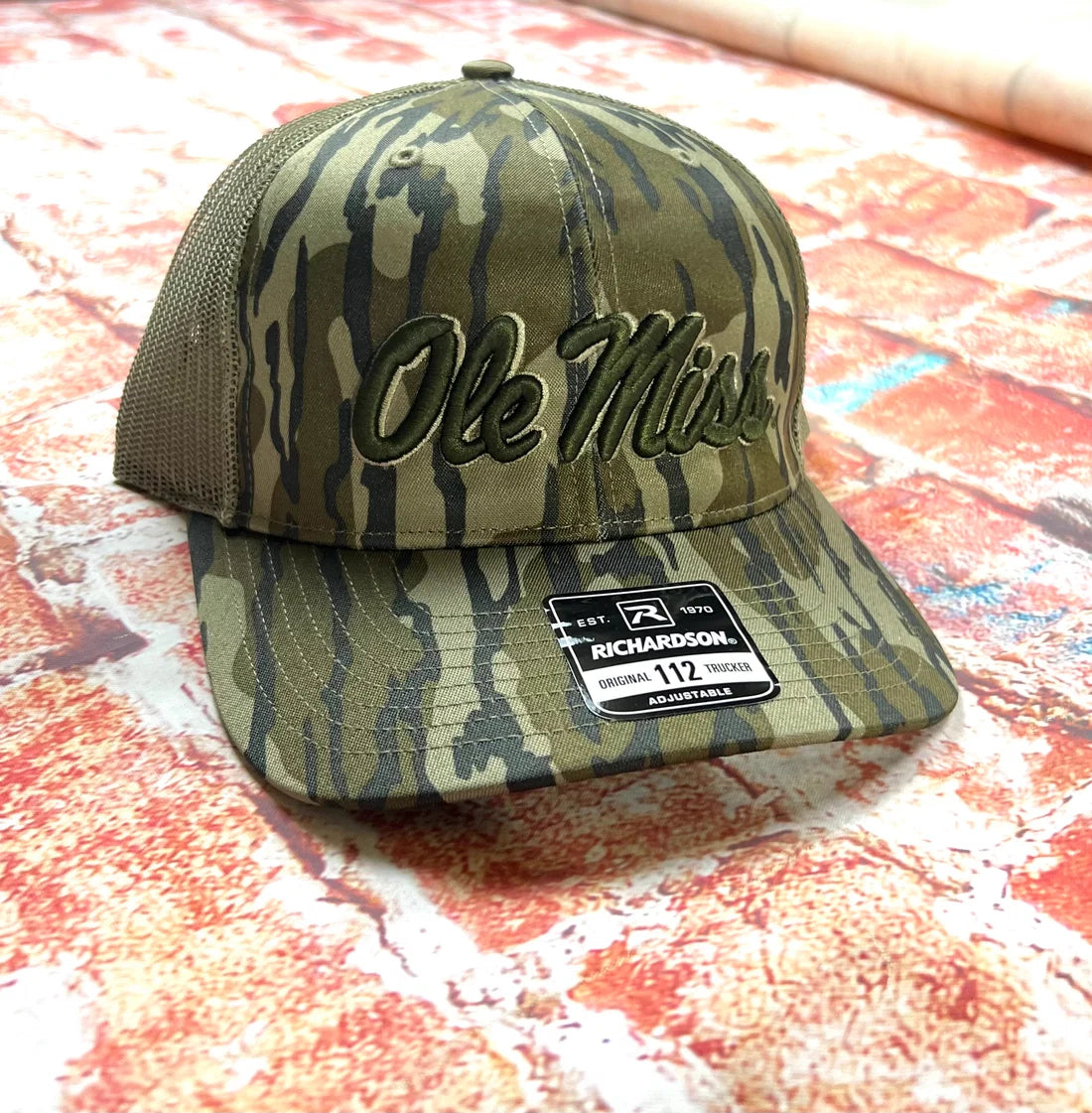 Camouflage baseball cap with 'Ole Miss' logo on a textured surface