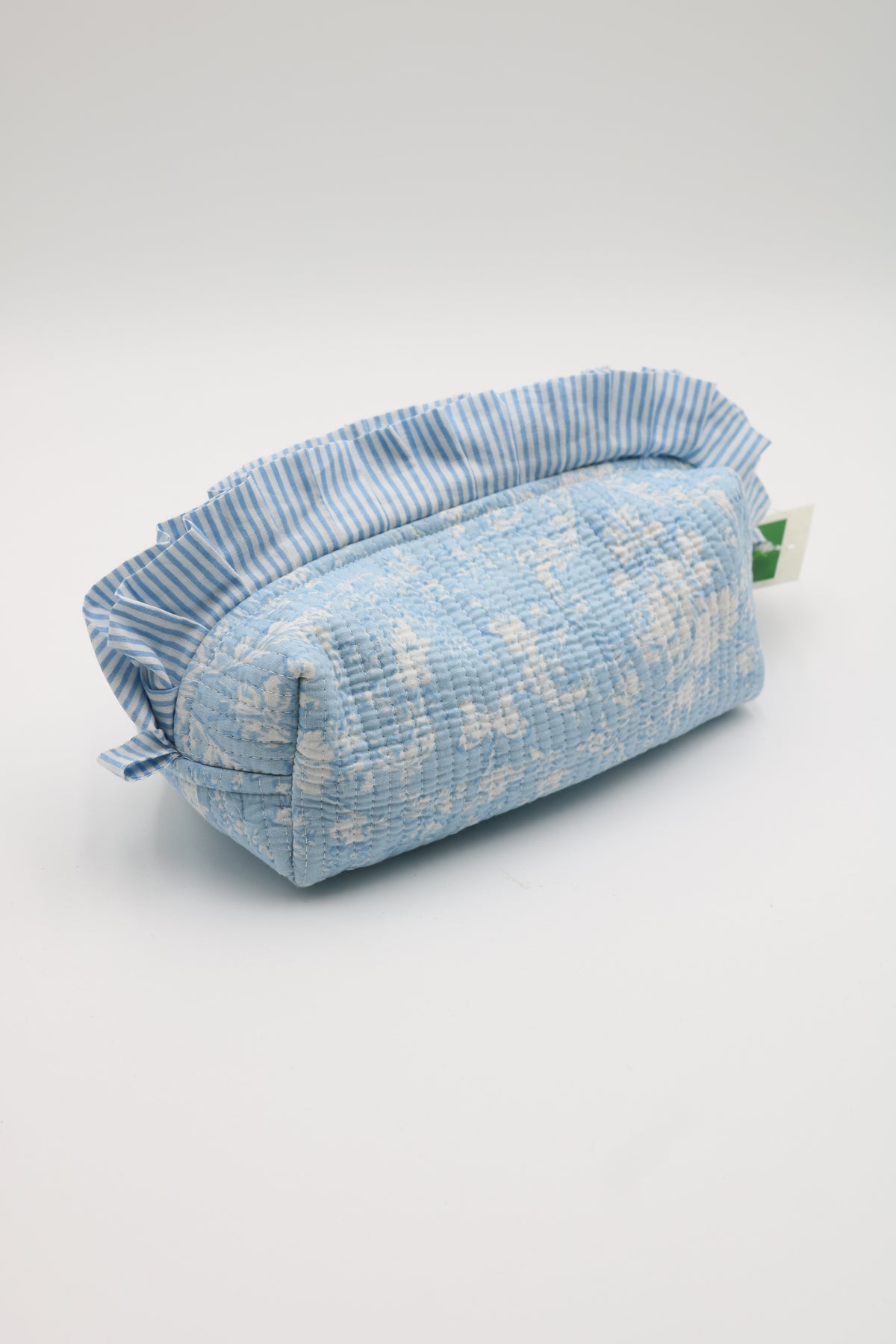A light blue and white patterned fabric pouch with a ruffled top edge, photographed on a clean light gray studio background.