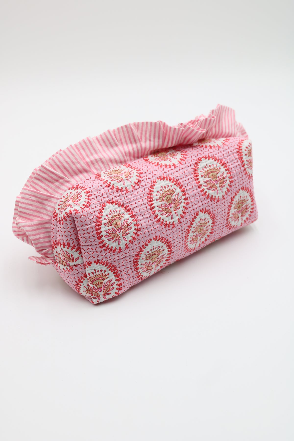 A pink fabric pouch with a ruffled edge, featuring a repeating circular floral pattern in pink, red, and white, shown on a plain white background.