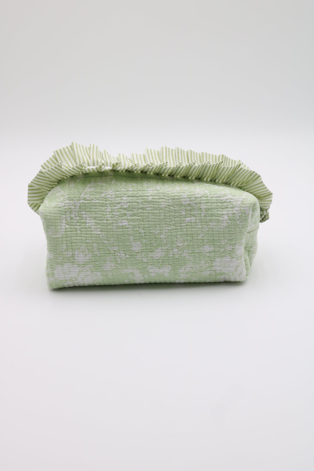 A light green textured fabric pouch with a ruffled top edge, photographed against a plain light gray studio background.