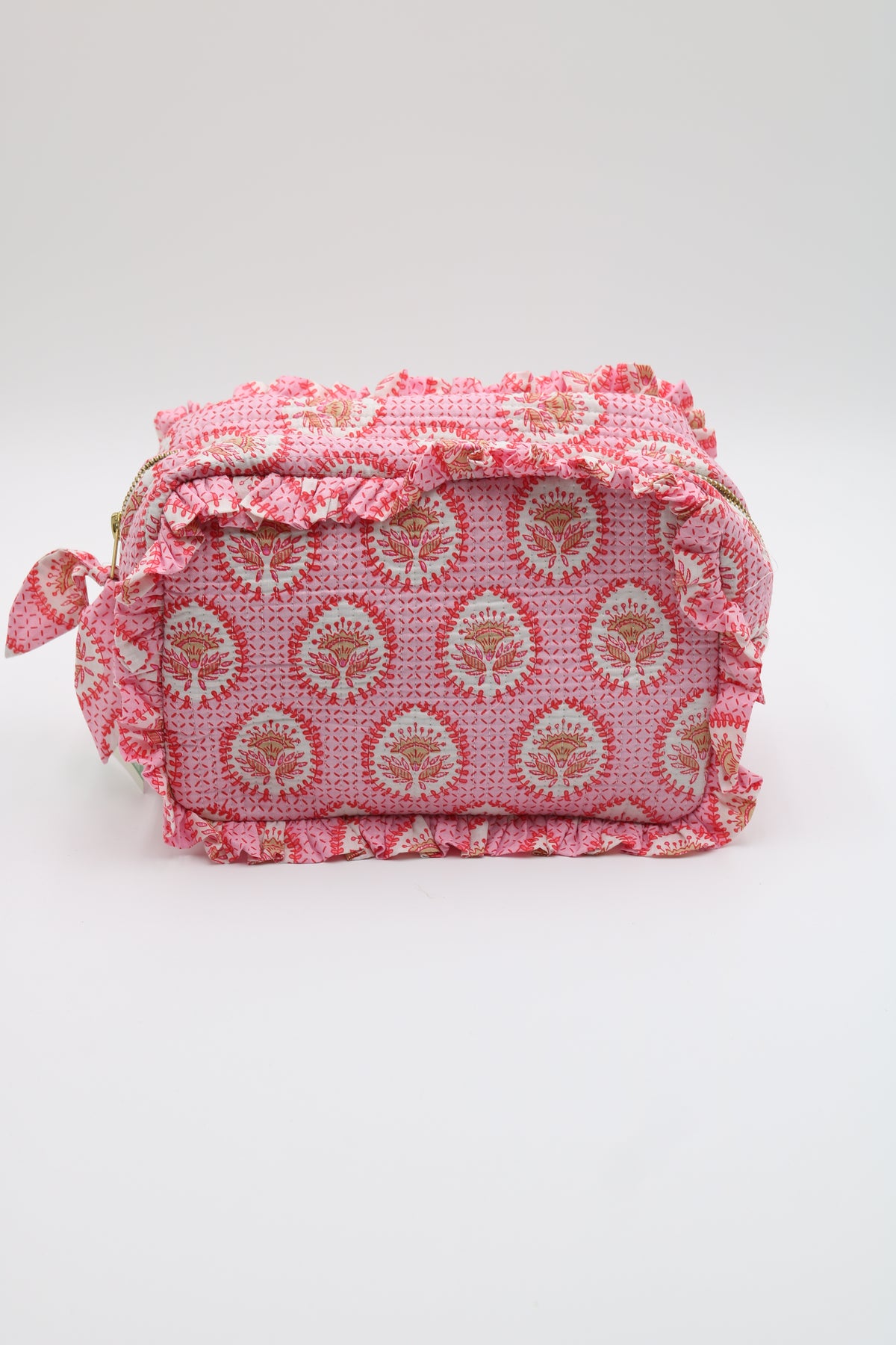 A pink patterned fabric pouch with ruffled trim and a small side tie, photographed on a plain light background.