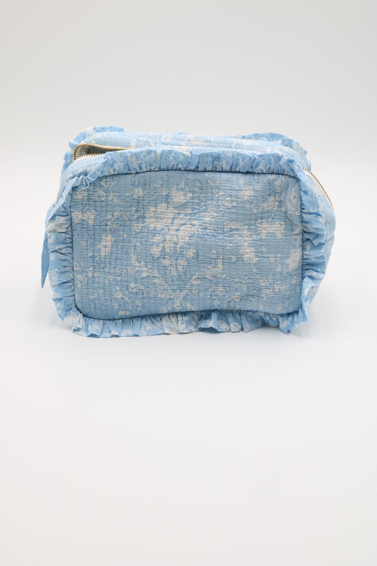 A light blue crinkled fabric cosmetic bag with ruffled trim, shown from the back on a clean white background.