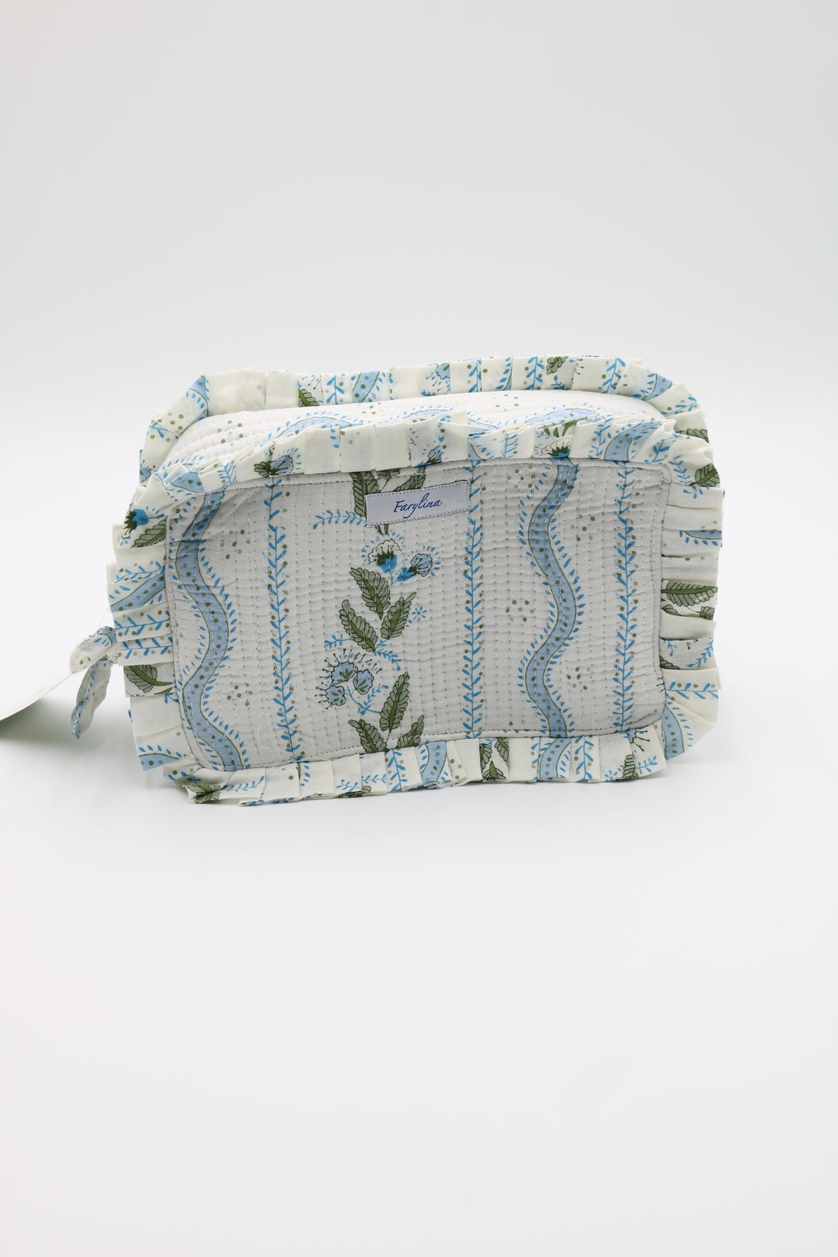 A small fabric cosmetic pouch with a ruffled edge, featuring a white background with blue wavy stripes, floral motifs, and green leaves. A small fabric tag is attached to the left side.
