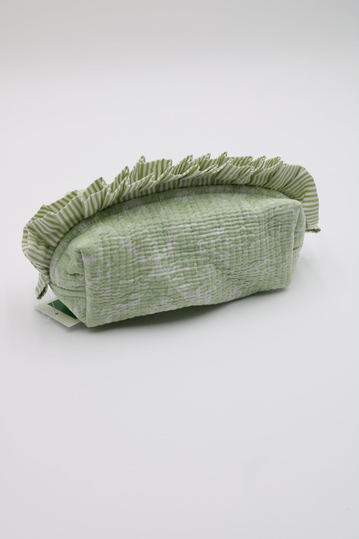A sage green textured fabric pouch with a ruffled edge, shown hanging against a plain white wall.