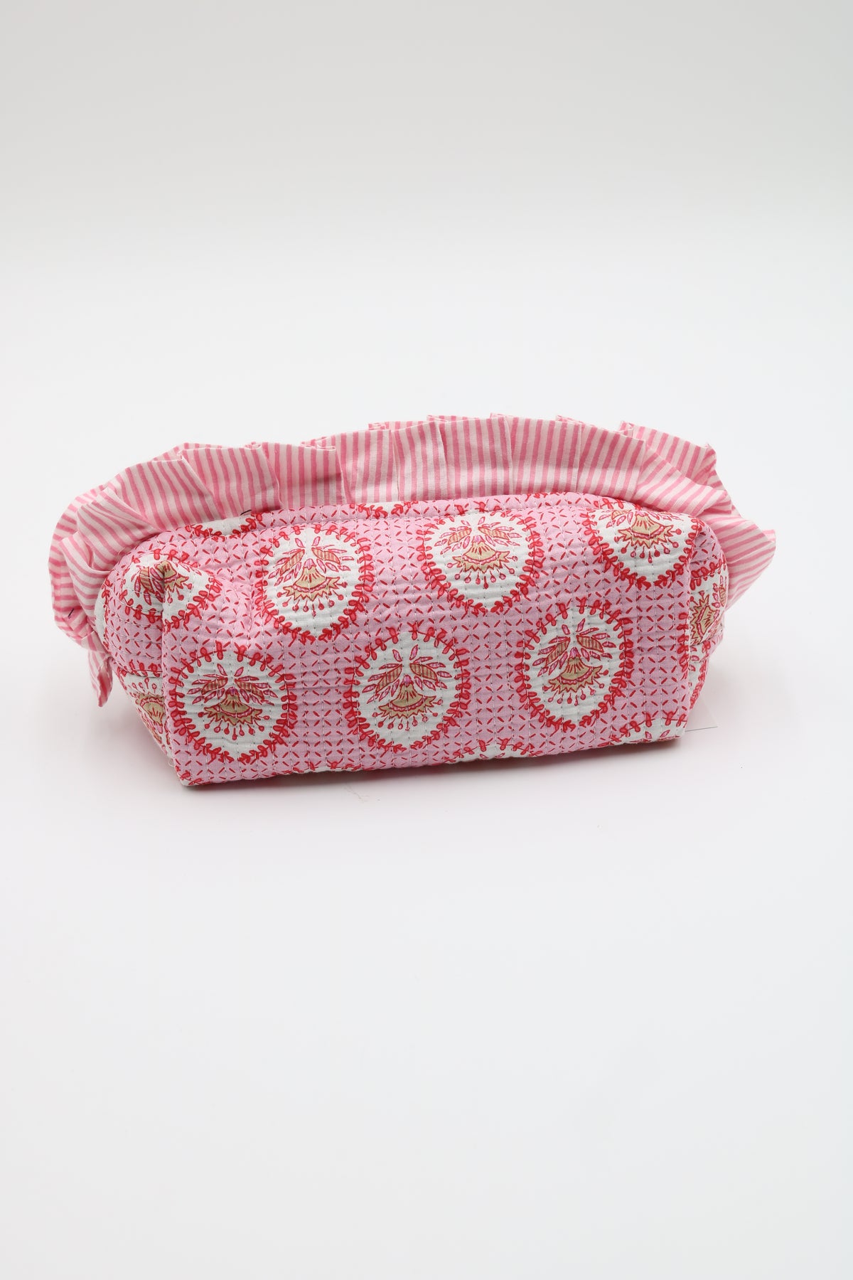 A small fabric pouch with a pink and white striped ruffled top edge and a pink body featuring a repeating white circular floral pattern, shown on a plain light gray background.