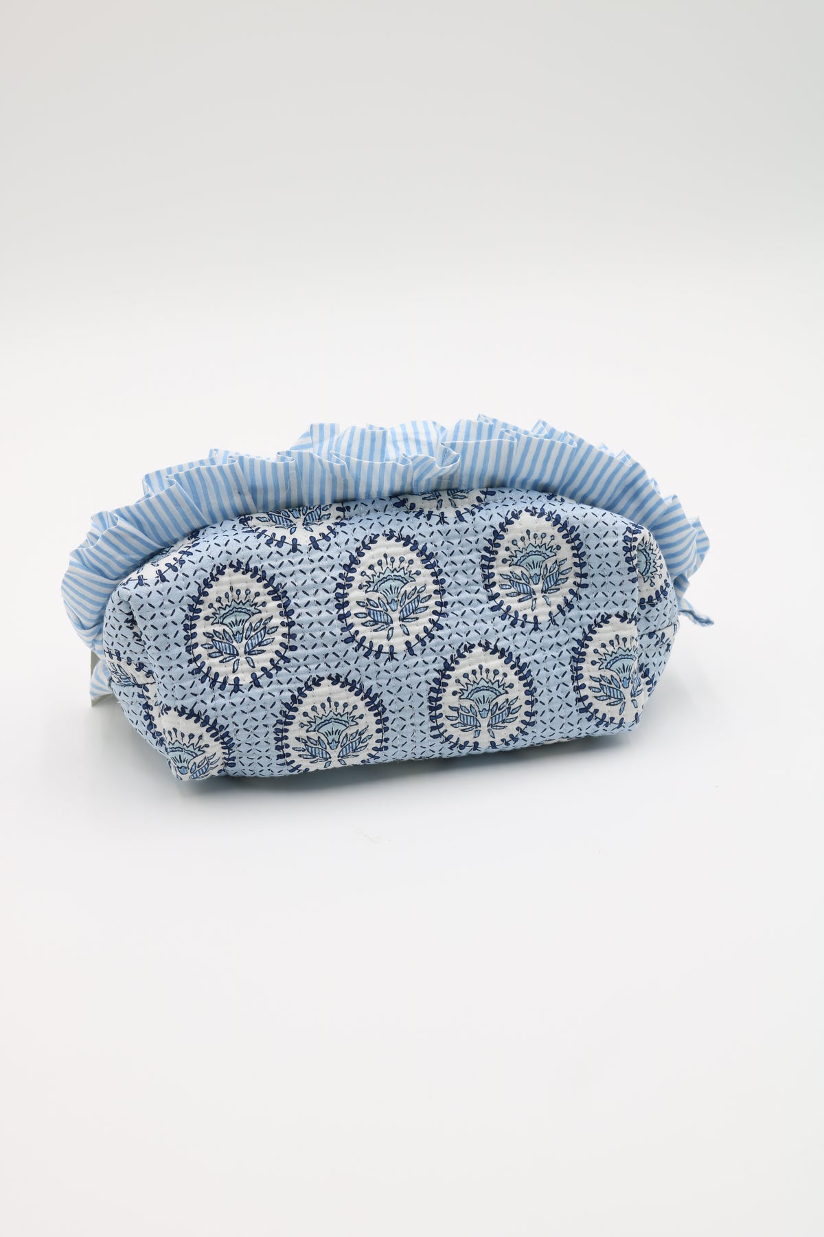 A handmade light blue and white crochet pouch with a striped fabric ruffle trim, photographed on a seamless white background.