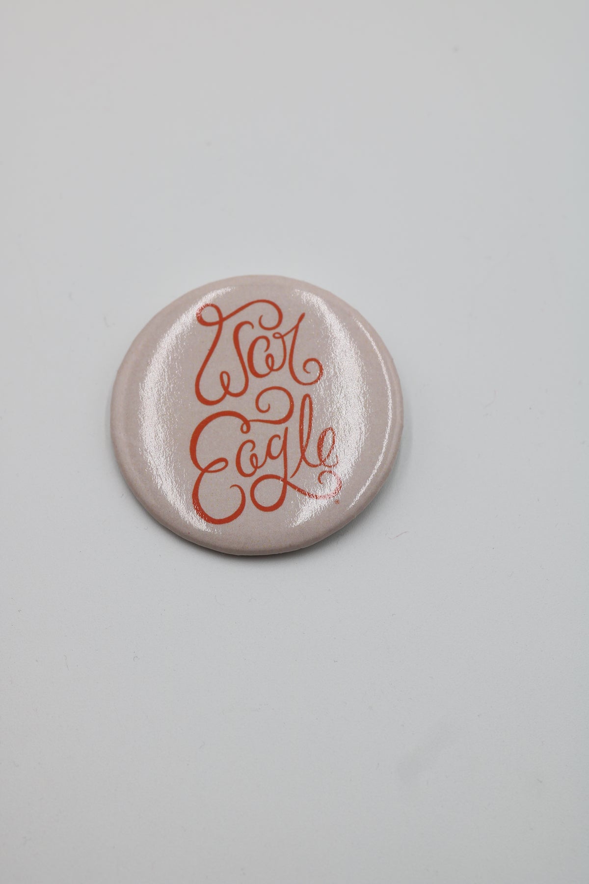 A round, glossy pinback button badge with a pale pink background and red cursive text reading 'Love People' in a stylized script, shown on a neutral light gray background.