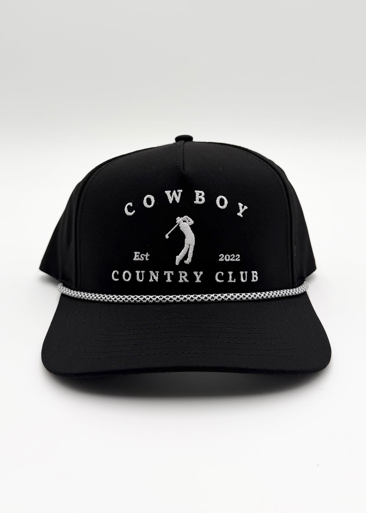 A black baseball cap with white embroidered text reading 'COWBOY COUNTRY CLUB' and a golfer silhouette on the front, plus a silver chain detail across the brim, shown on a light gray background.