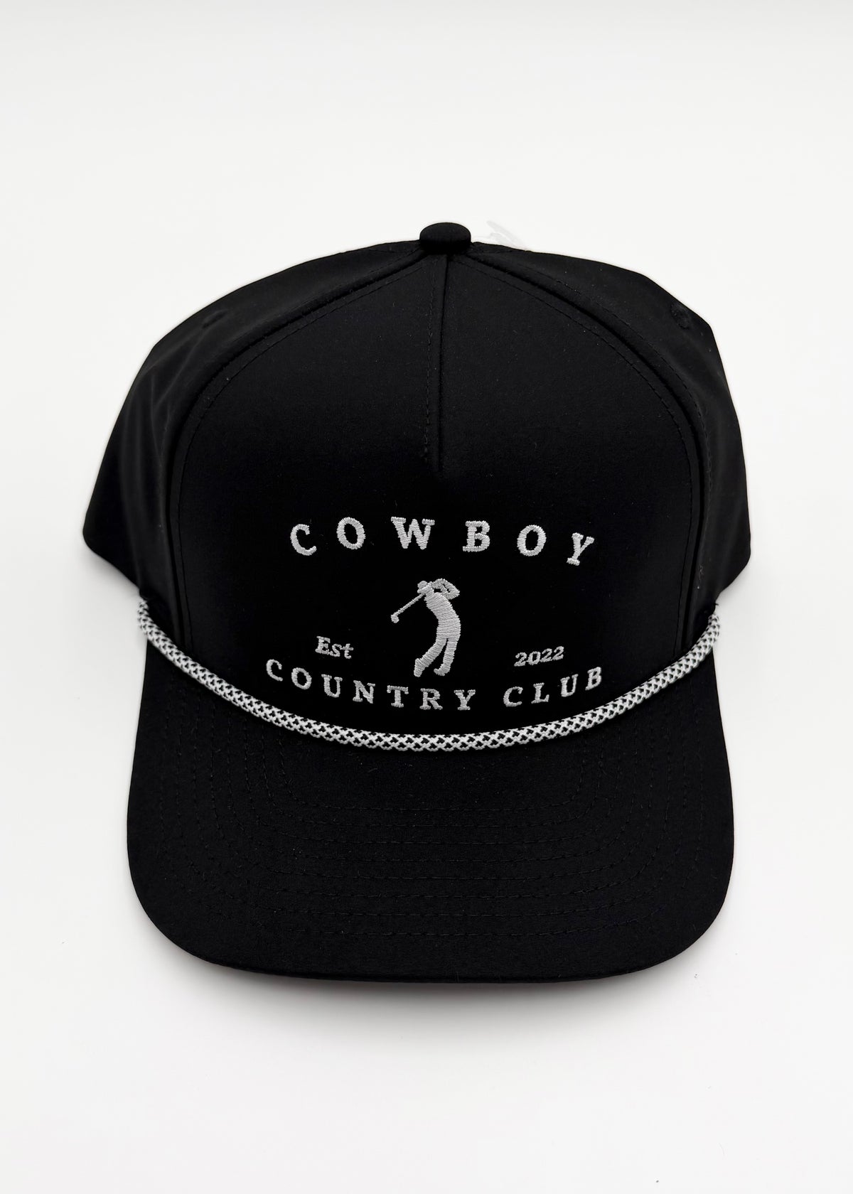 A black baseball cap with white embroidered text reading 'COWBOY COUNTRY CLUB' and a small golfer silhouette, plus a decorative white chain-like line across the front, shown on a plain light background.