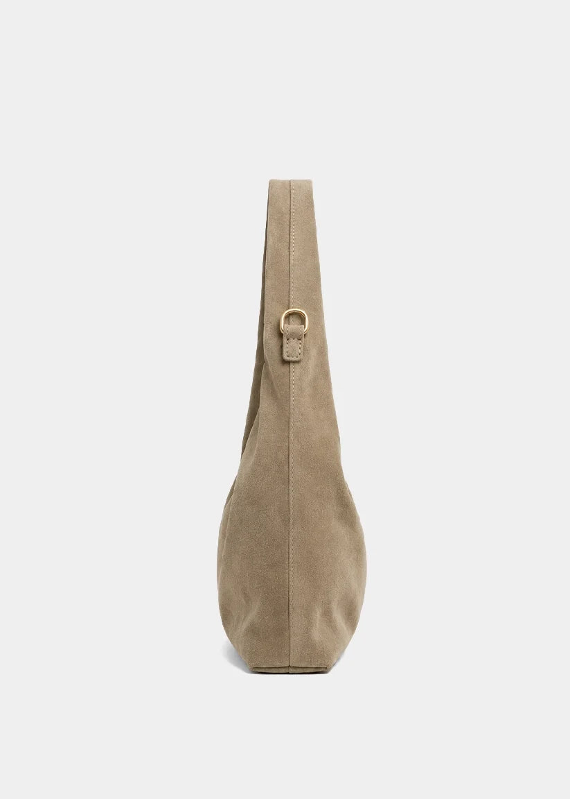 A taupe suede shoulder bag shown from the side profile against a light gray background.