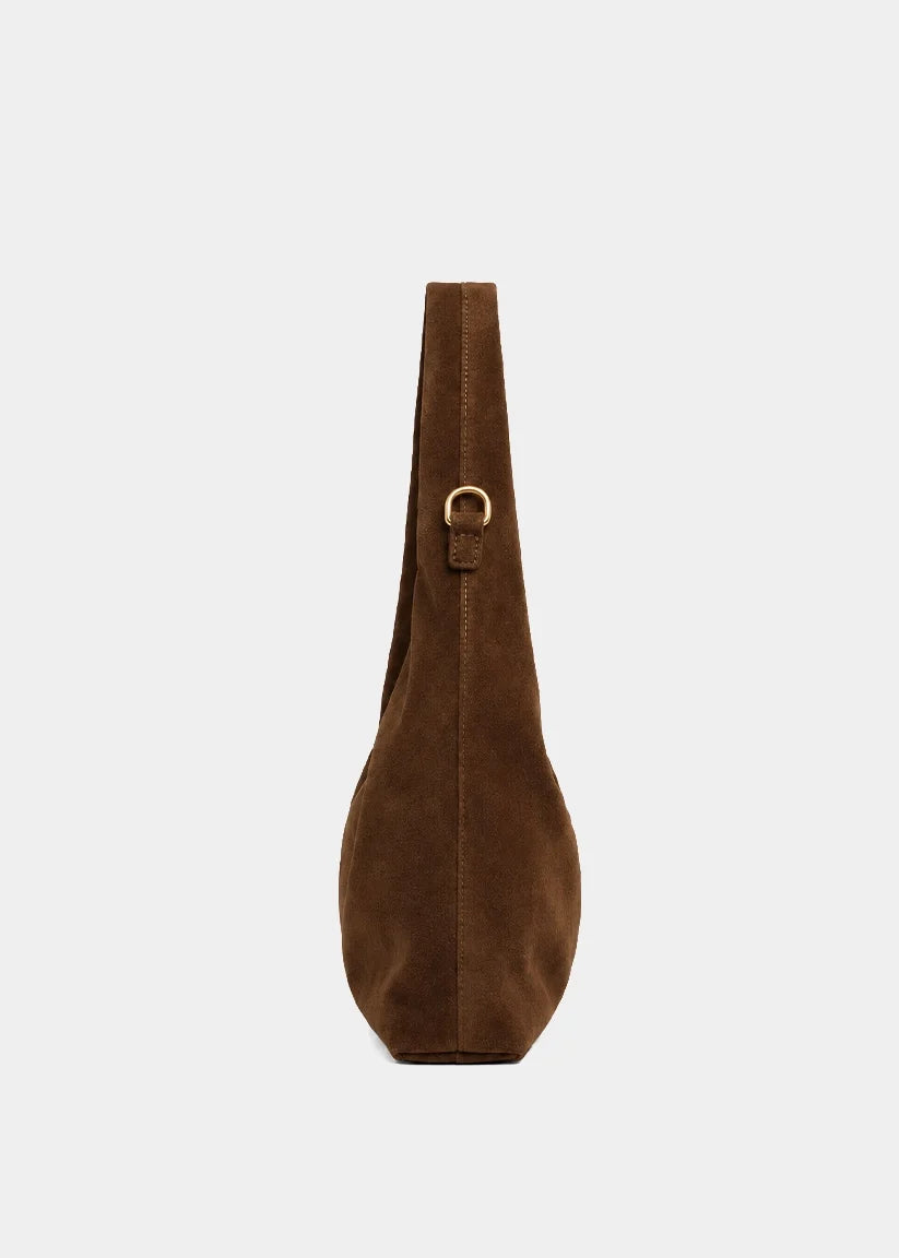 A brown suede shoulder bag shown from the side against a light gray background, featuring a gold-tone metal ring detail on its strap.
