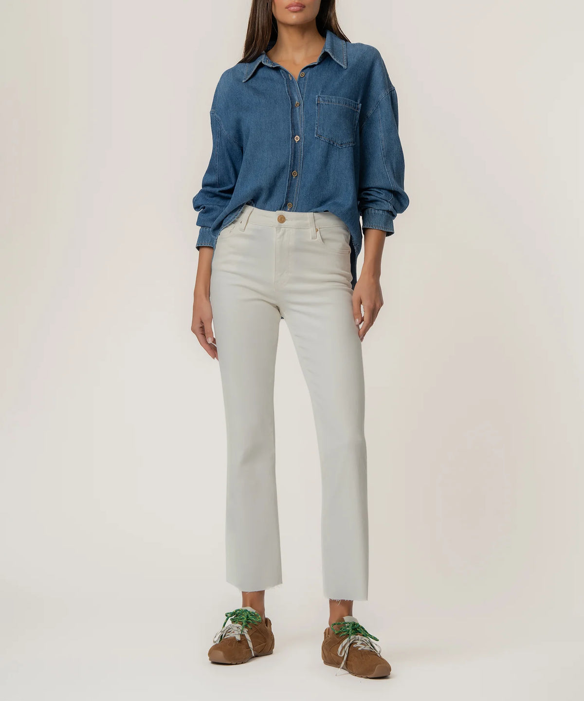 Person wearing a blue denim shirt and light gray jeans on a white background