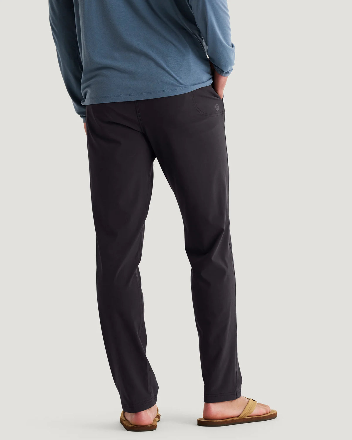 Person wearing black pants and a blue top on a plain background