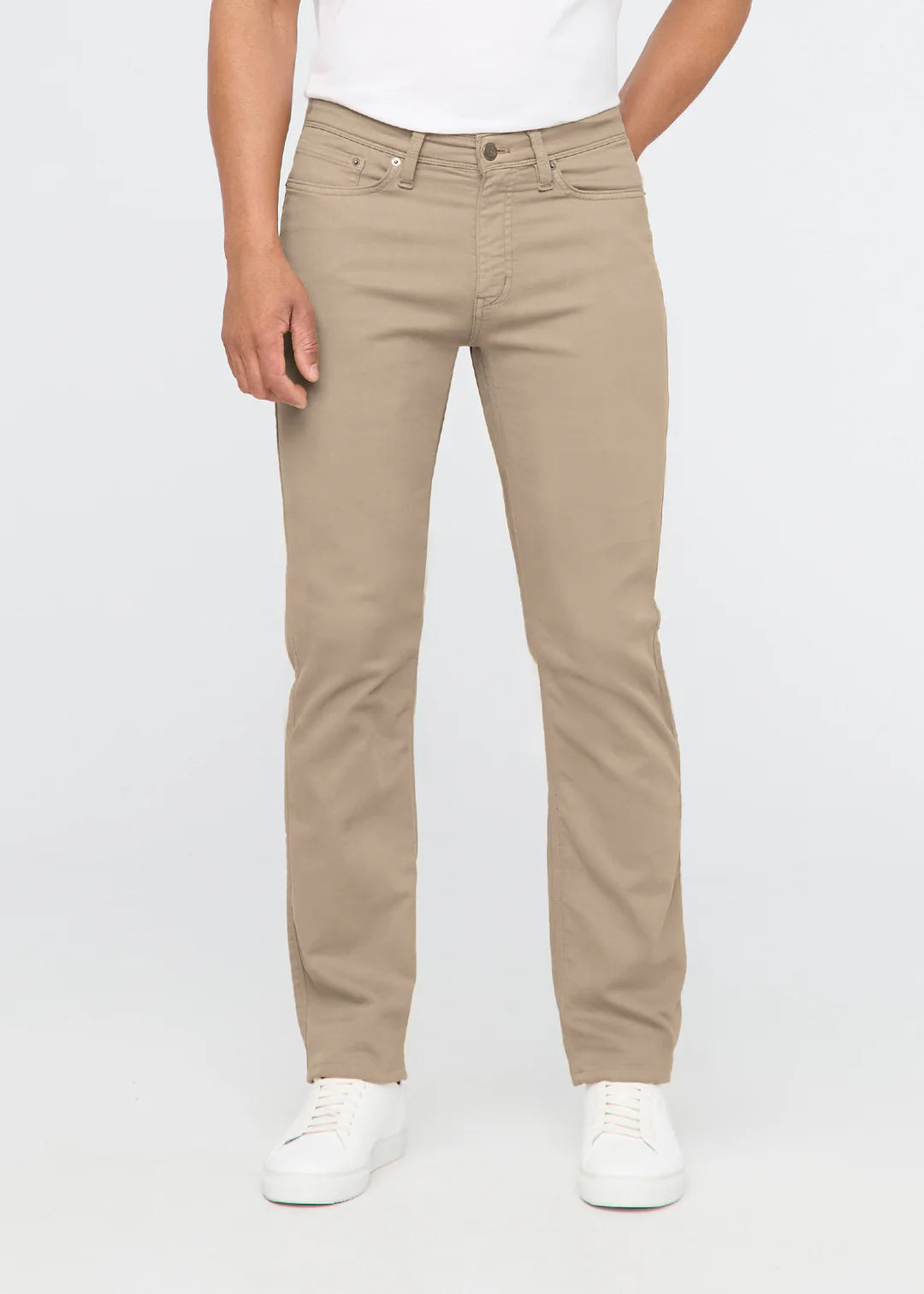 Man wearing a white t-shirt, khaki pants and white shoes standing in front of a white background. 
