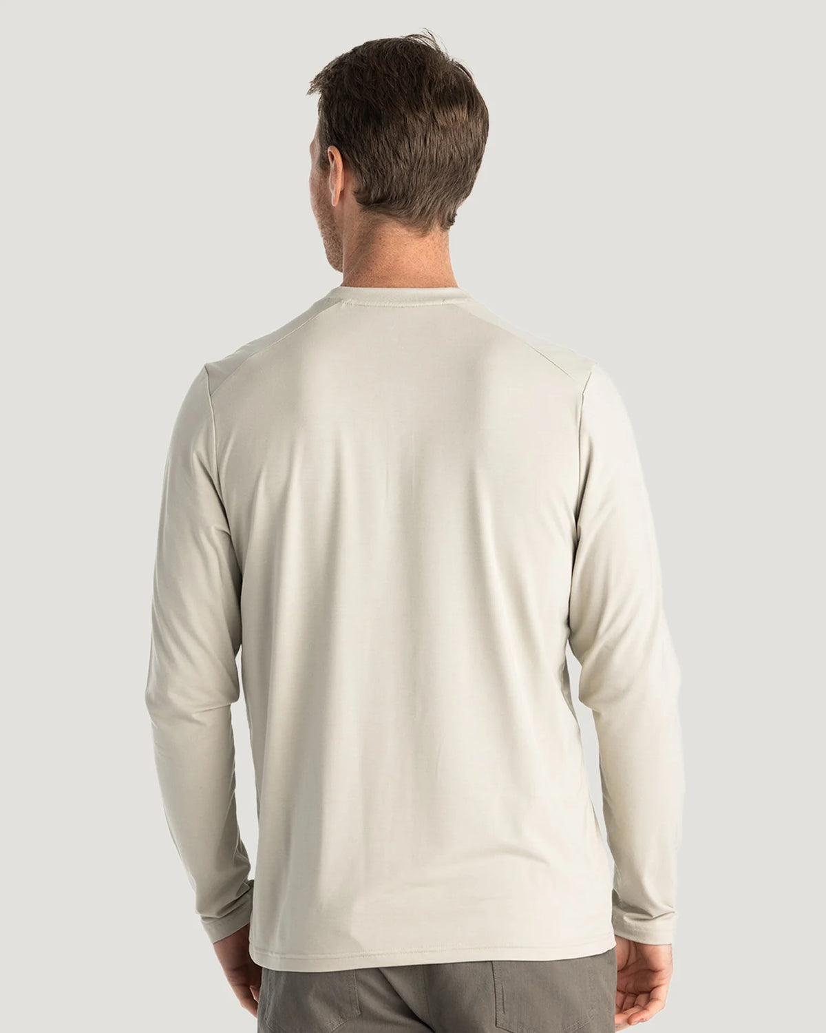 Man wearing a beige long-sleeve shirt on a light gray background