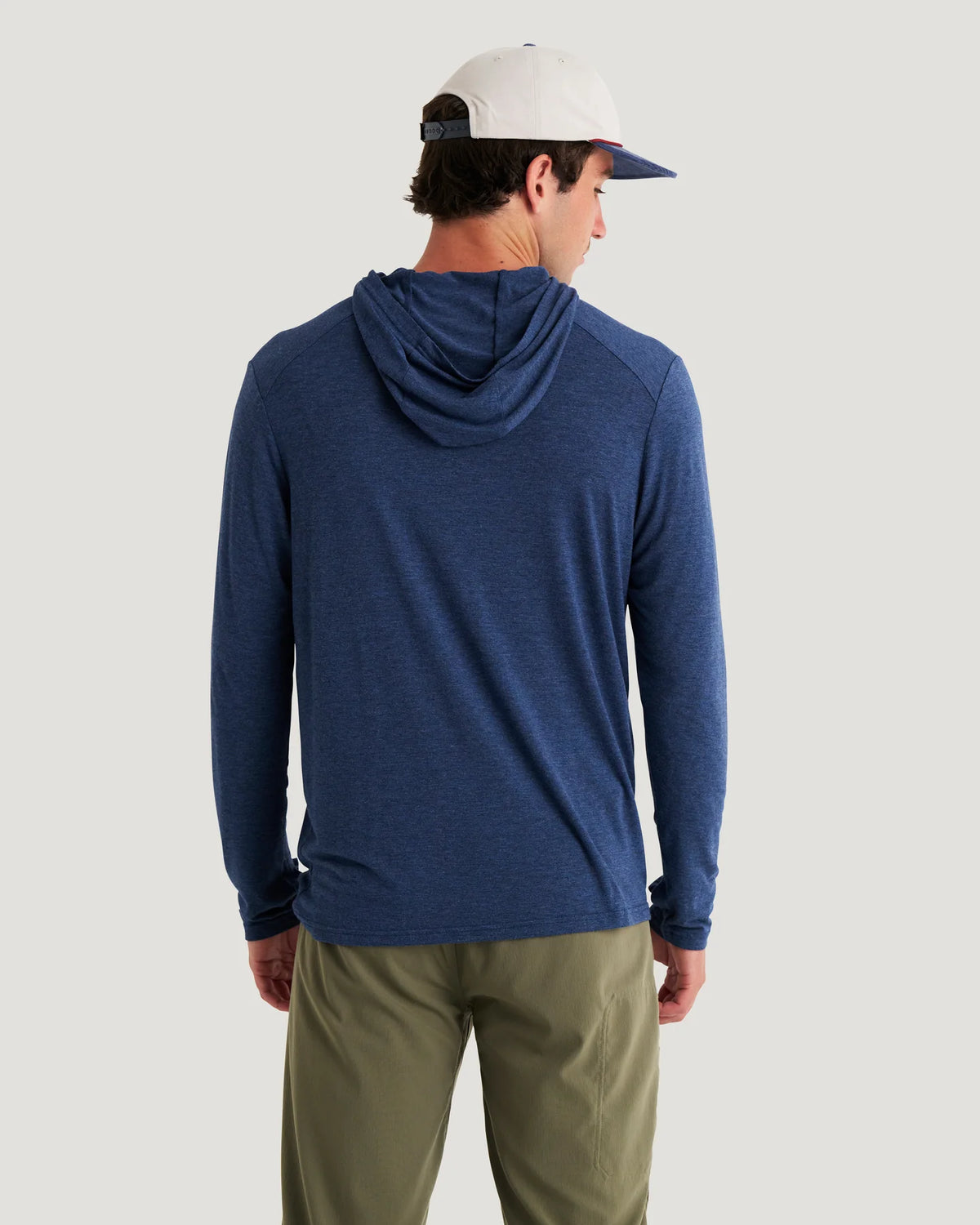 Person wearing a blue hooded long-sleeve shirt and green pants on a light gray background