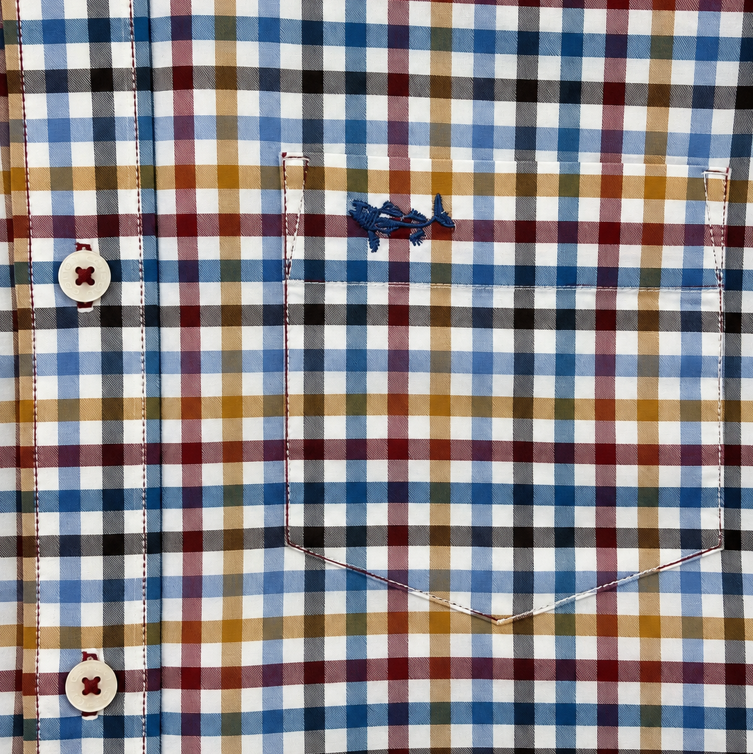 Close-up of a plaid button-up shirt fabric with a chest pocket and visible blue embroidered logo thread.