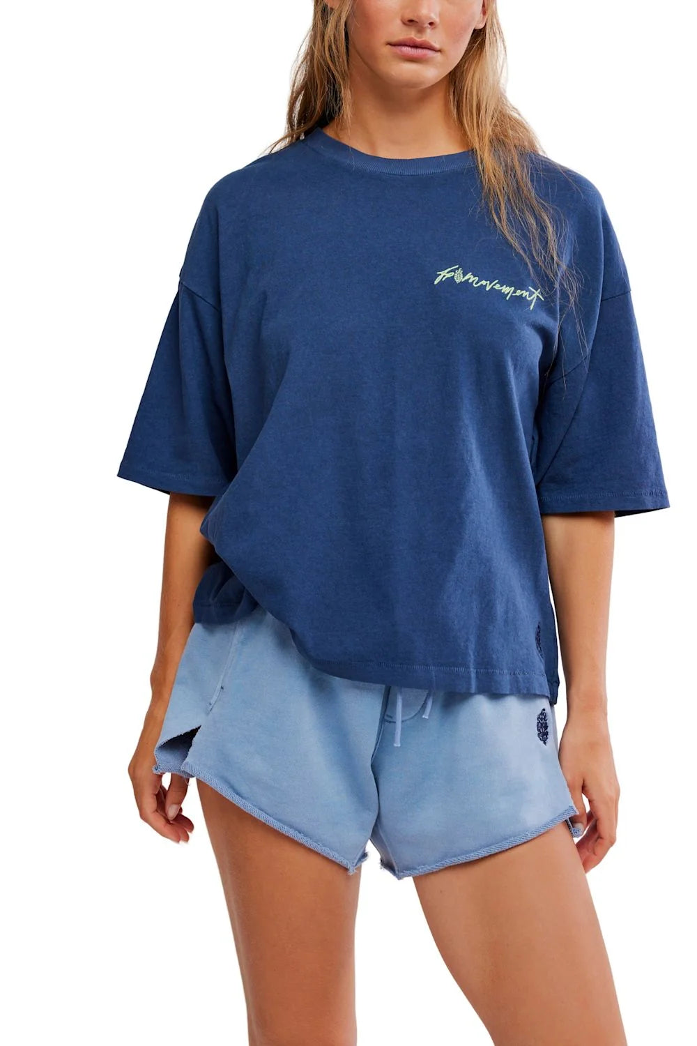 Person wearing a blue oversized t-shirt and shorts set with a brand logo on a white background