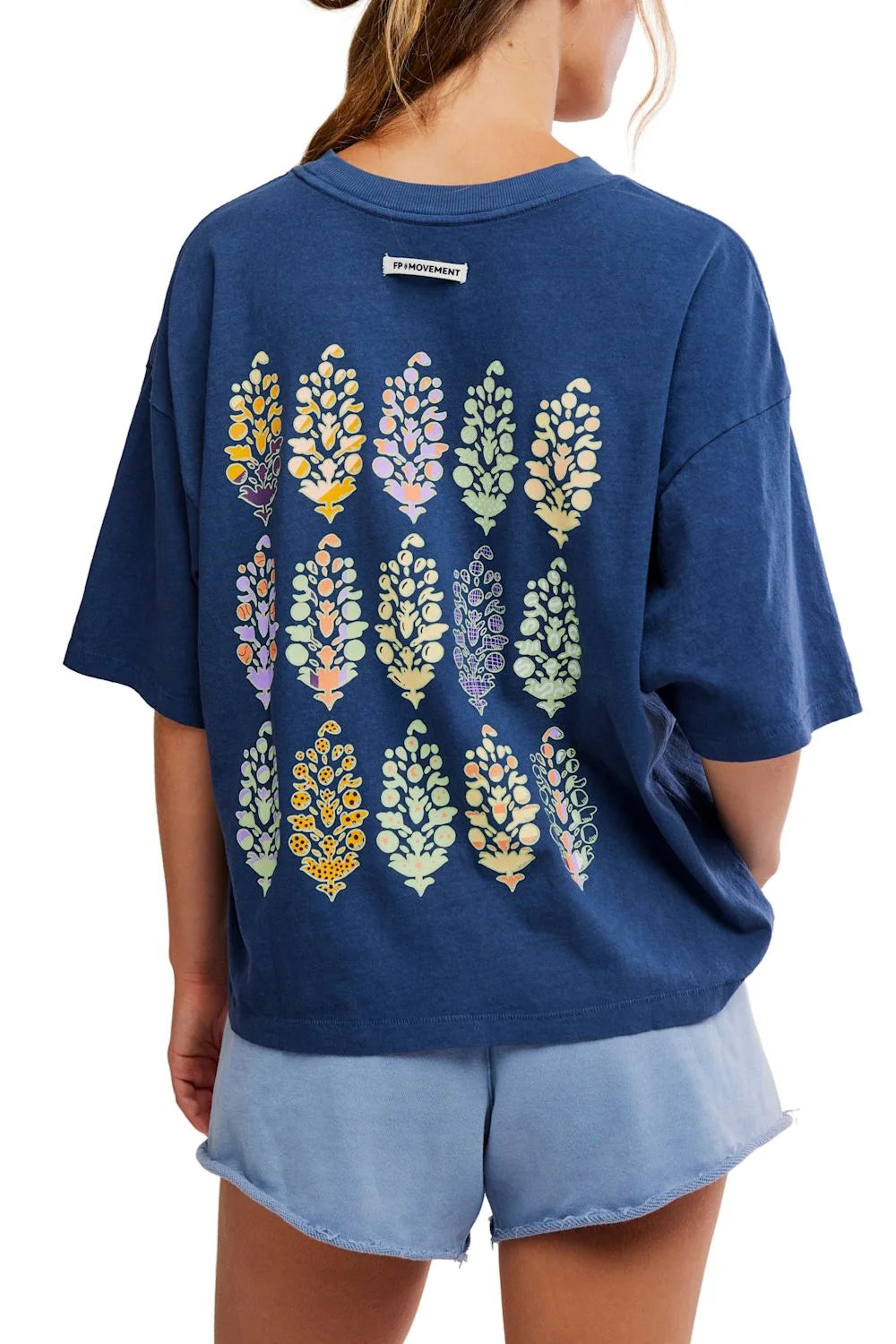Navy blue t-shirt with colorful leaf pattern on the back, worn by a person.