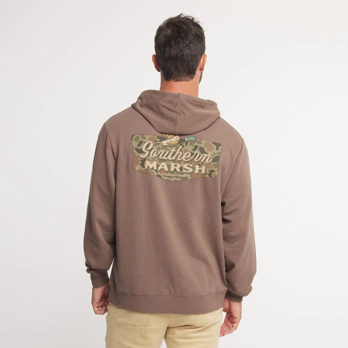 A man viewed from behind wearing a brown pullover hoodie with a large camouflage graphic on the back that reads 'Southern Marsh'.