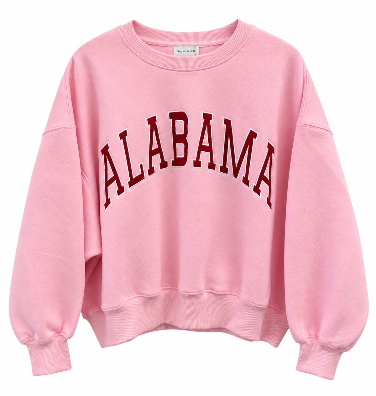 A light pink crewneck sweatshirt featuring the word 'ALABAMA' printed across the chest in a dark red arched collegiate font.