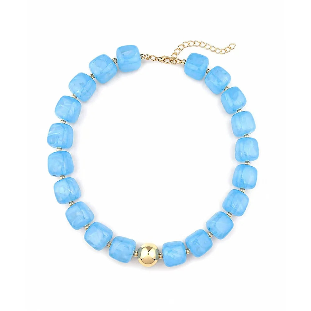 A beaded necklace featuring light blue faceted square beads separated by small gold spacer rings, with a central gold bead and a gold chain extender clasp, shown on a plain white background.