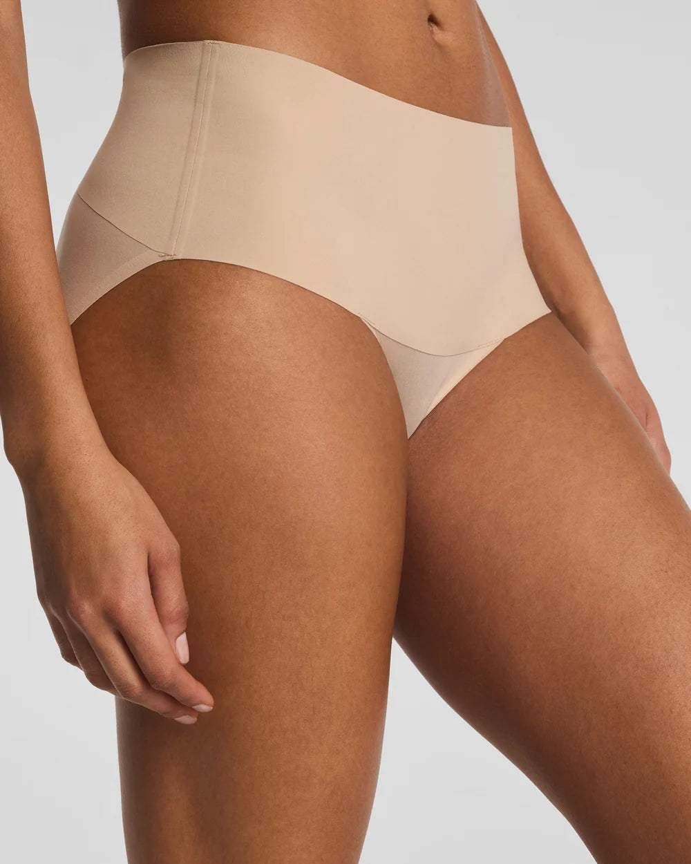 Beige high-waisted underwear worn by a person on a white background
