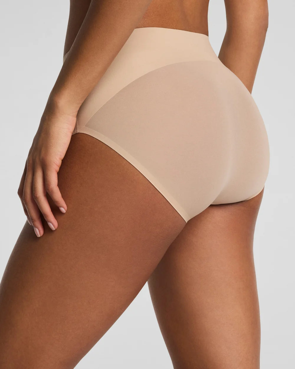 Beige high-waisted underwear worn by a person on a white background