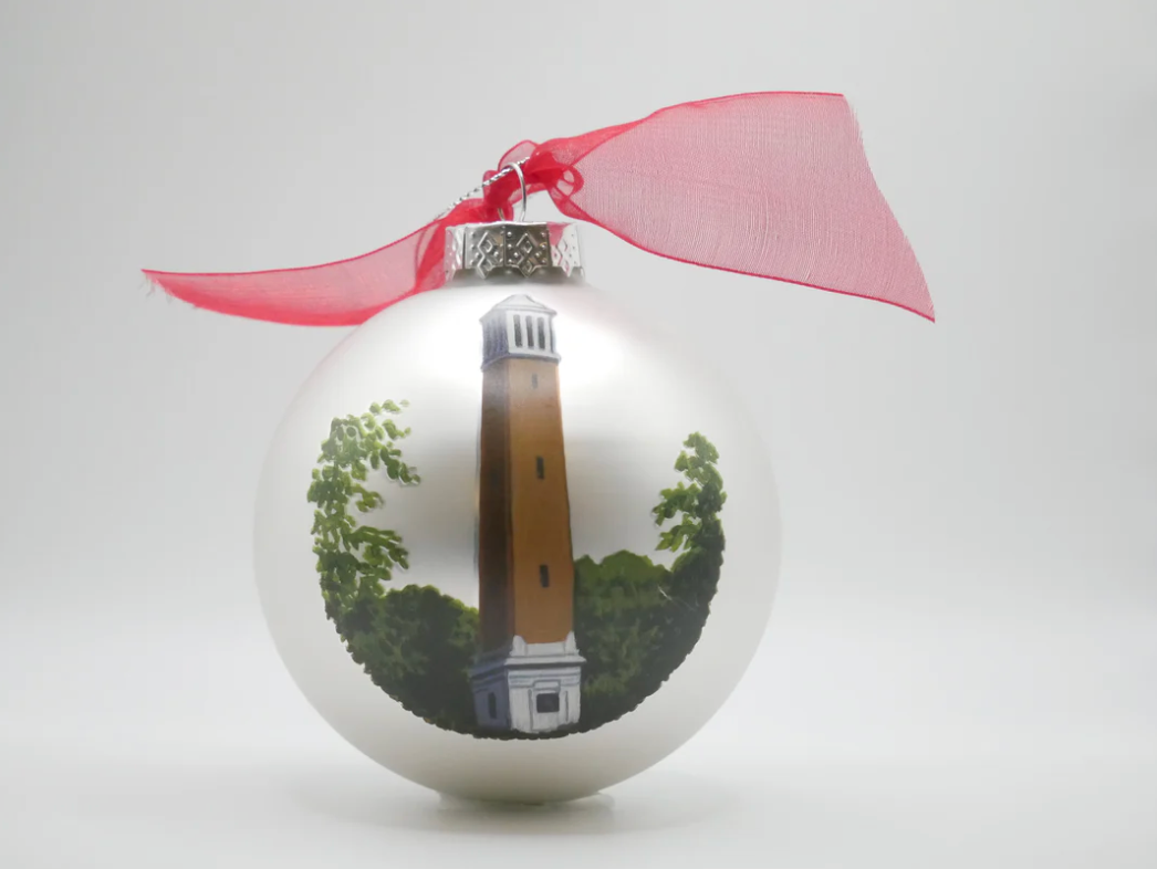 Silver Christmas ornament with a red ribbon featuring a tower and tree design on a white background