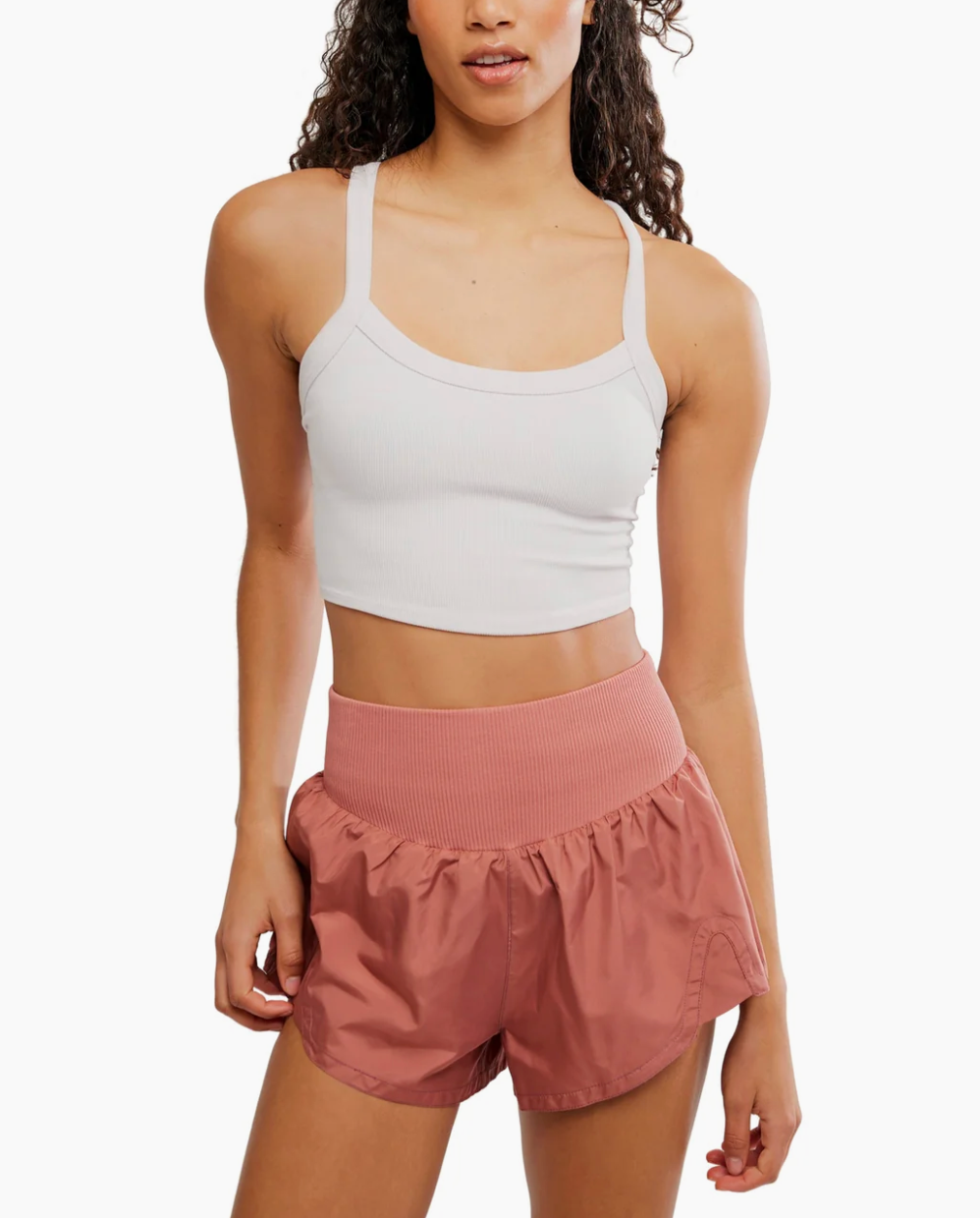 Woman wearing a white tank top and pink shorts on a white background