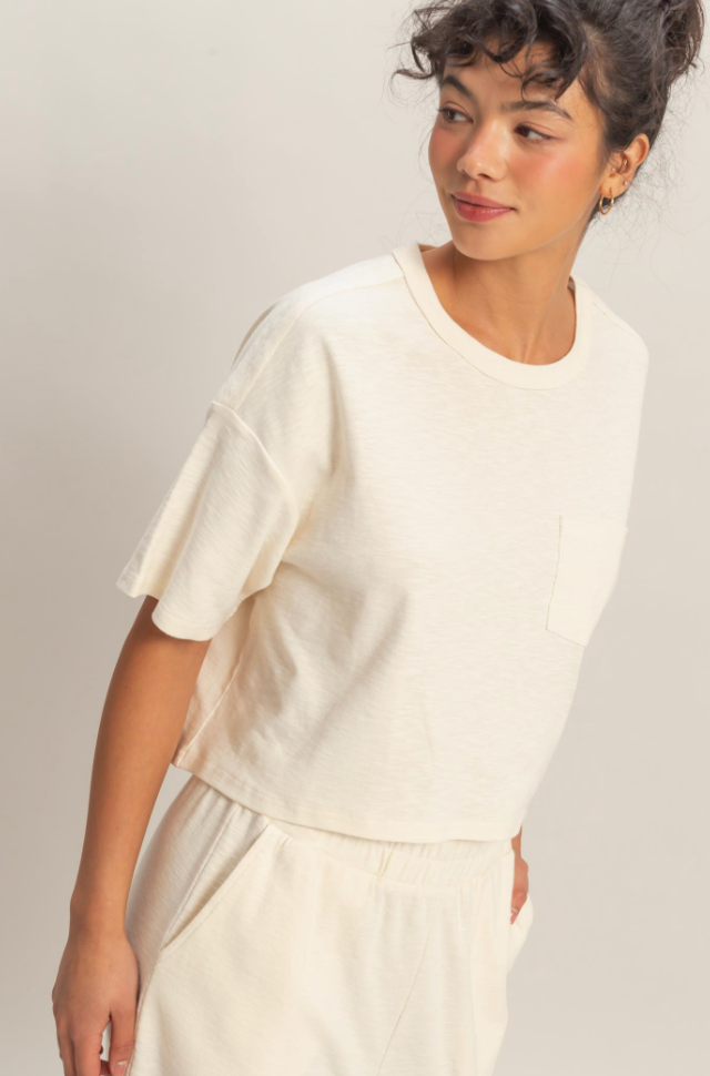 Woman wearing a white top and pants against a plain background