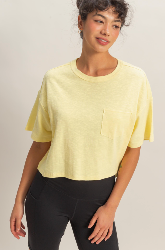 Woman wearing a yellow top and black pants on a plain background