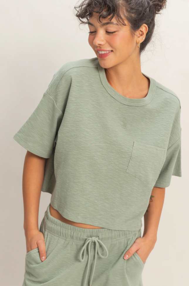 Woman wearing a green t-shirt and pants against a plain background