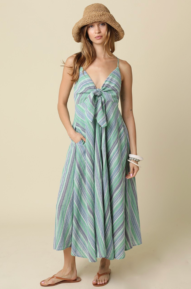 Woman wearing a green and purple striped dress with a straw hat on a beige background
