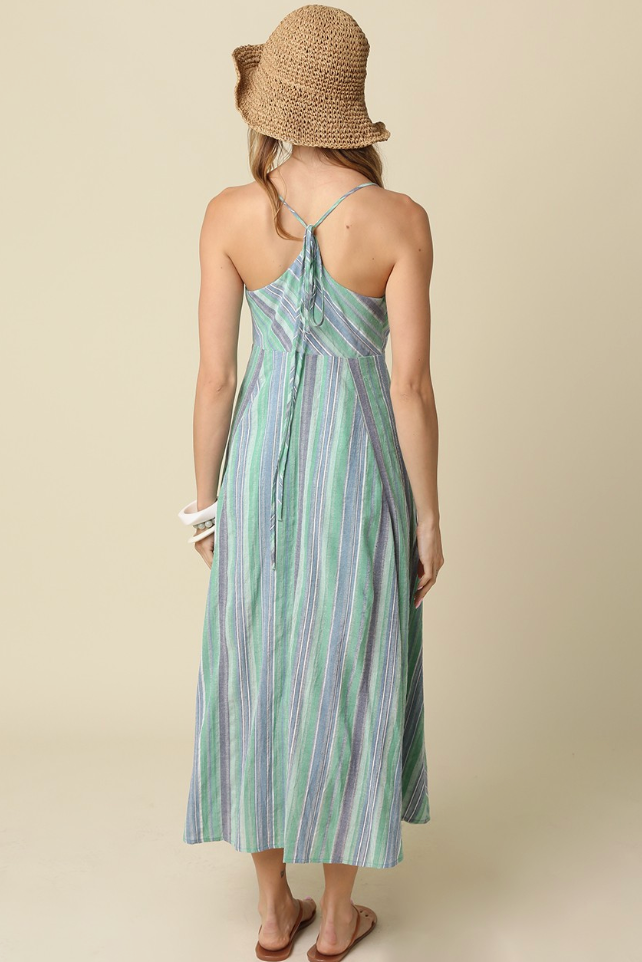 Woman wearing a green and white striped dress with a straw hat on a beige background
