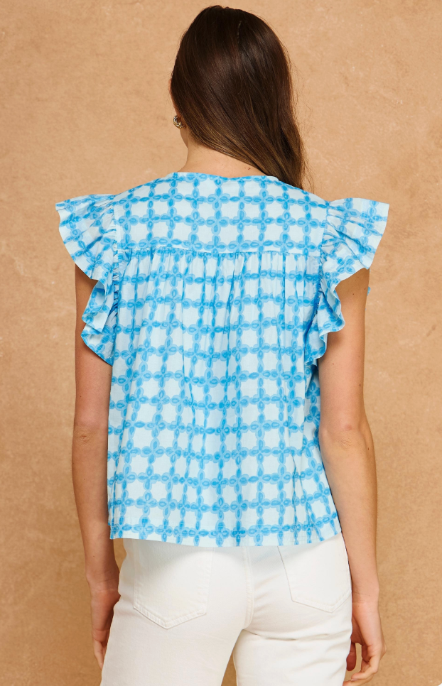 Woman wearing a blue and white checkered top with ruffled sleeves against a beige background