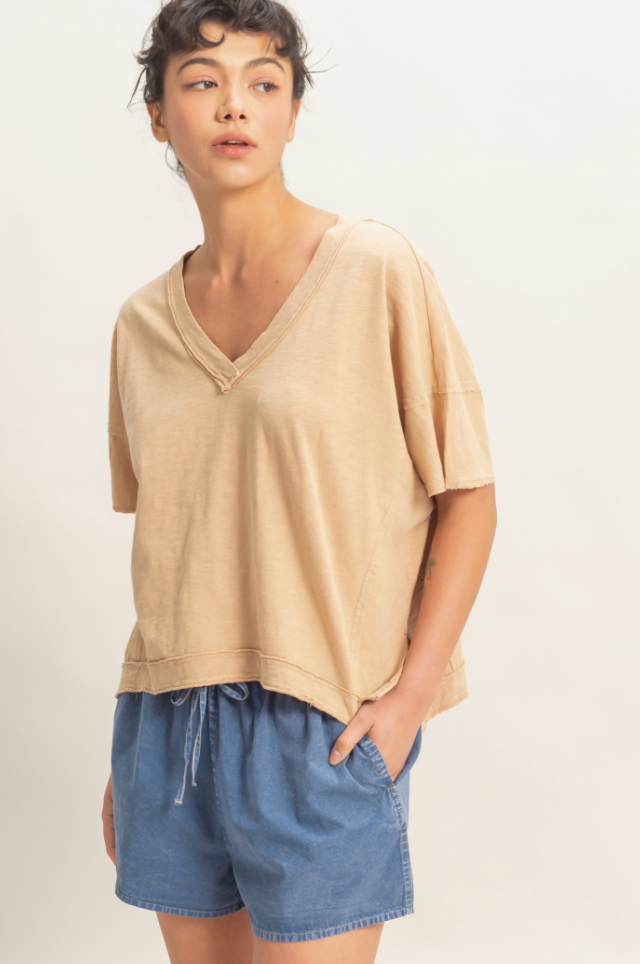 Woman wearing a beige top and blue shorts on a plain background