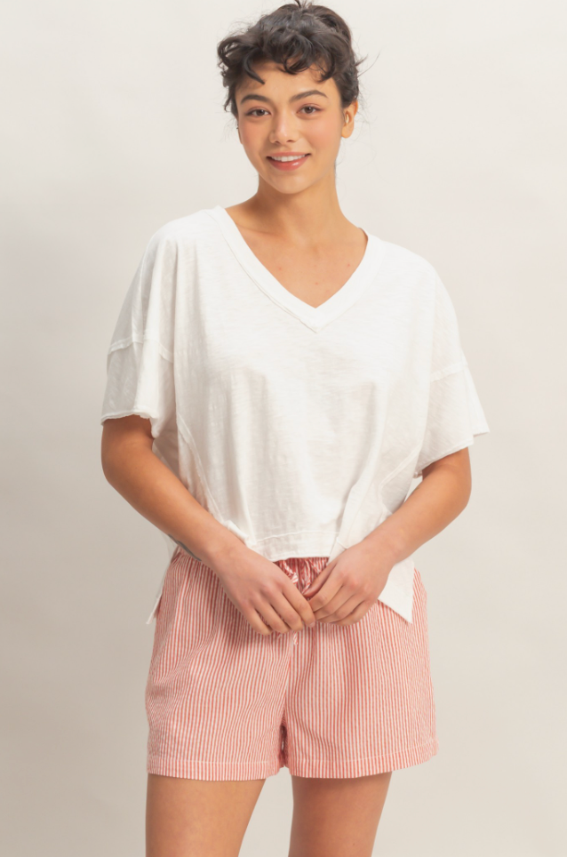 Woman wearing a white top and pink shorts against a plain background