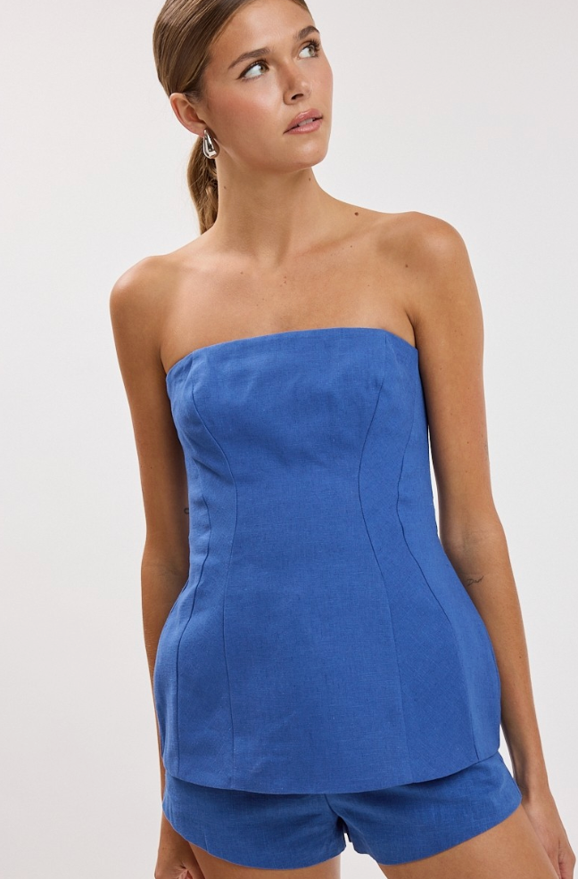 Woman wearing a blue strapless top and shorts on a white background