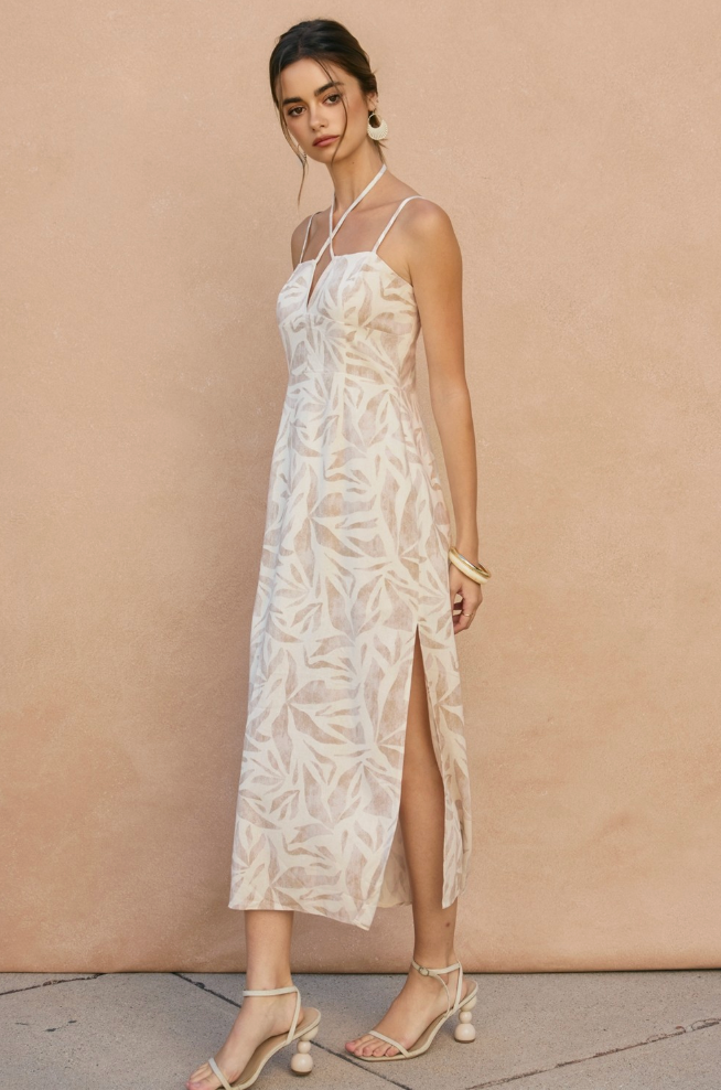 Woman wearing a white floral dress against a beige background
