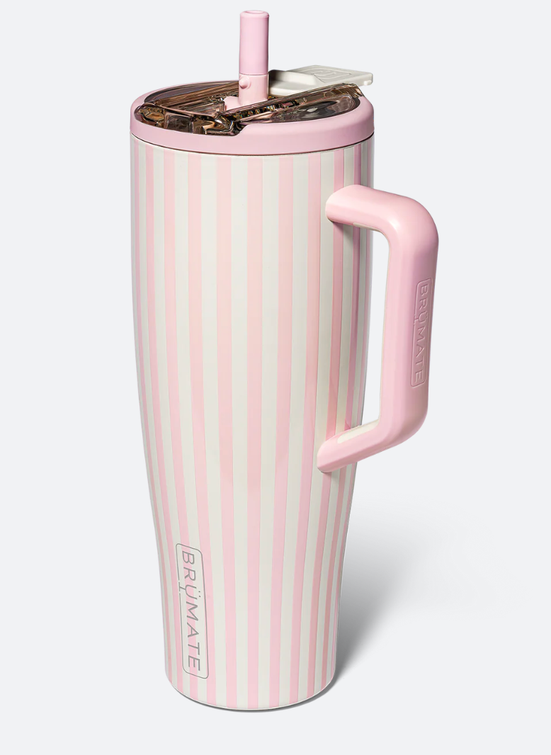 A pink and white vertically striped insulated travel tumbler with a matching pink handle and lid, featuring the BRUMATE brand name printed vertically near the bottom.