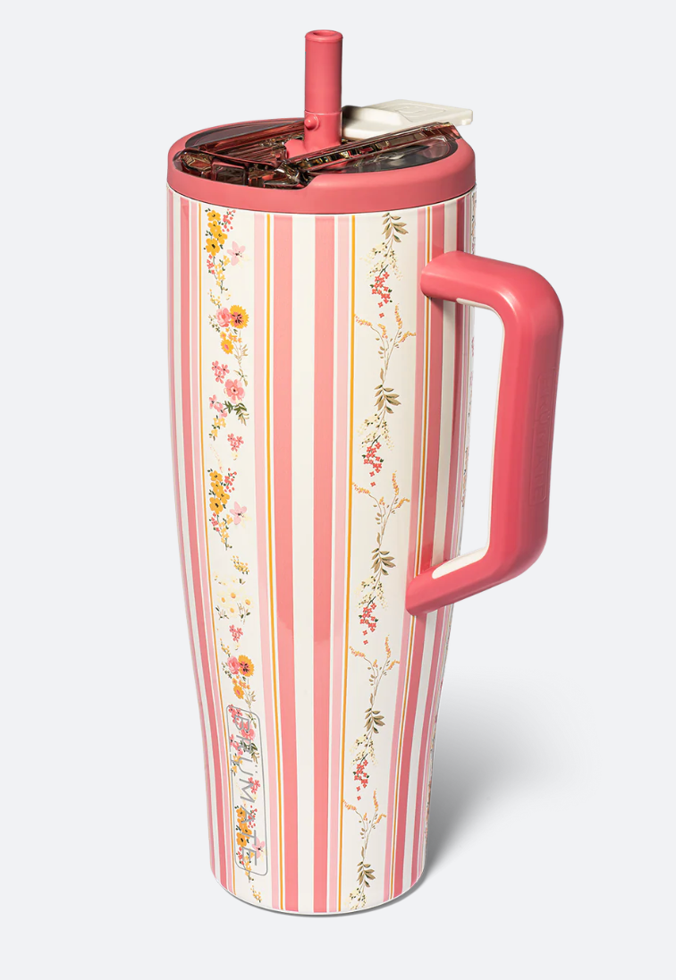 A tall insulated travel tumbler with a pink handle, pink lid, and straw, decorated with vertical pink and white stripes and delicate floral vine patterns, shown on a light gray background.