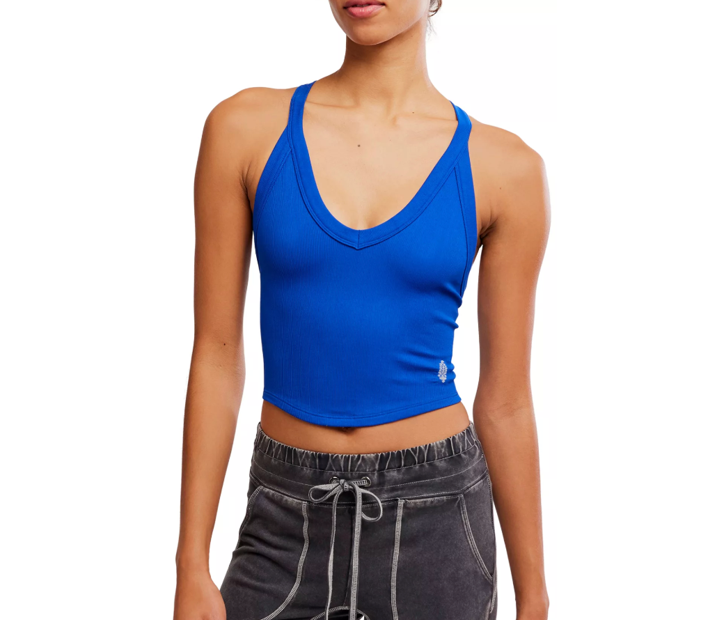 A woman wearing a bright royal blue scoop-neck crop tank top and dark gray drawstring sweatpants, shown from the nose down against a plain white background.