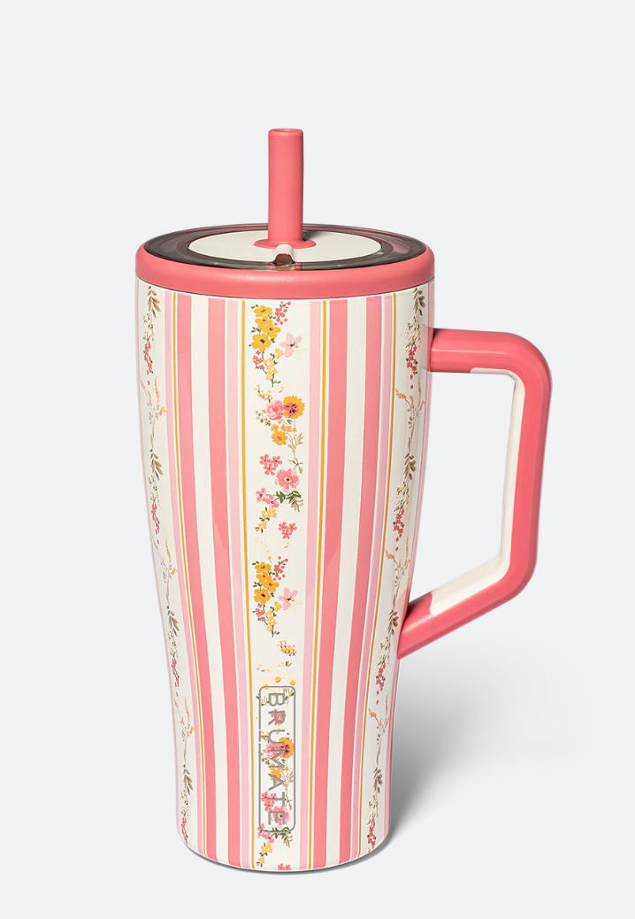 A tall insulated travel tumbler with a pink handle and straw, decorated with vertical pink and white stripes and delicate floral motifs, shown on a light gray background.