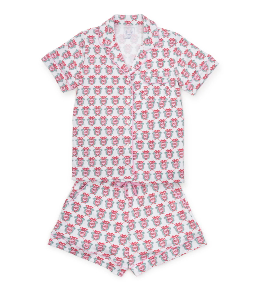 A two-piece girls' pajama set featuring a short-sleeve button-front top and matching shorts, both printed with a repeating pattern of pink cartoon characters on a white background.