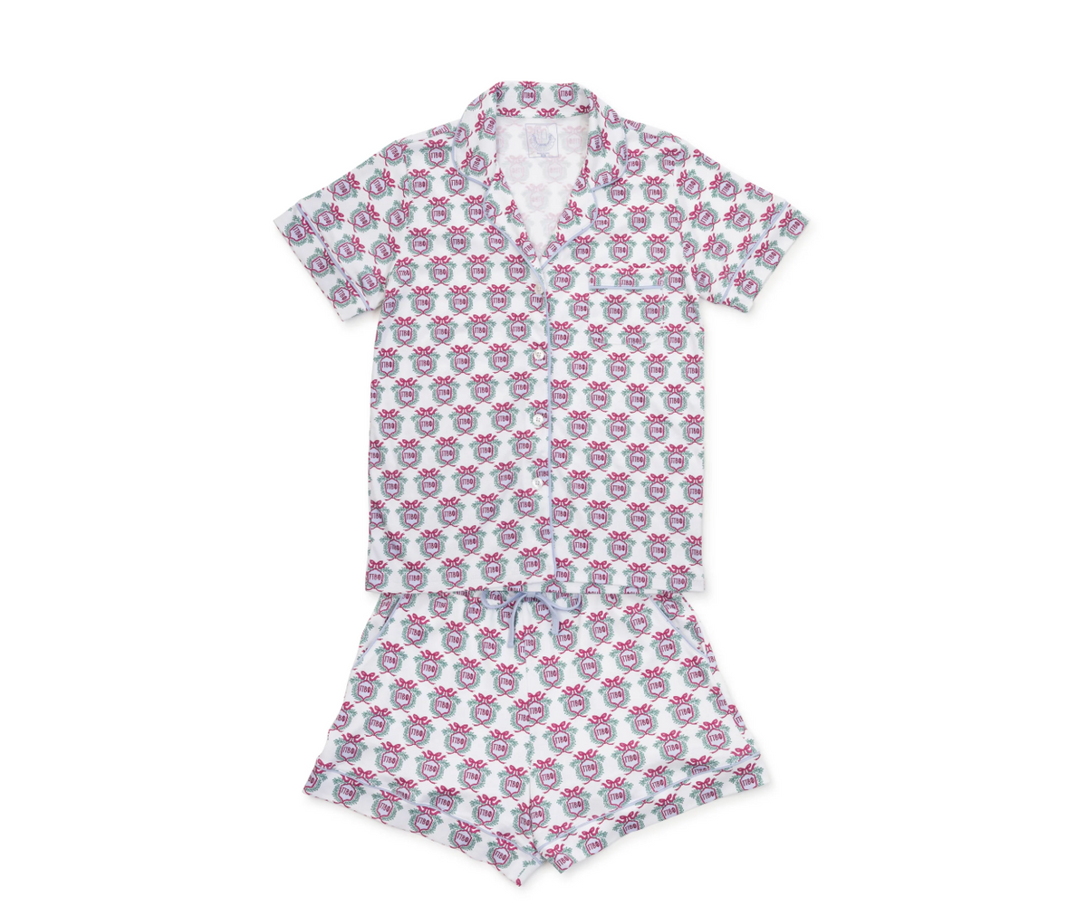 A two-piece short-sleeve pajama set featuring a white base fabric with an all-over repeating pattern of pink and gray cartoon-style faces, laid flat on a white background.