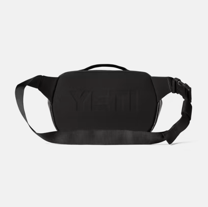 A black YETI fanny pack with a matching black strap and buckle, shown from the back on a light gray background.