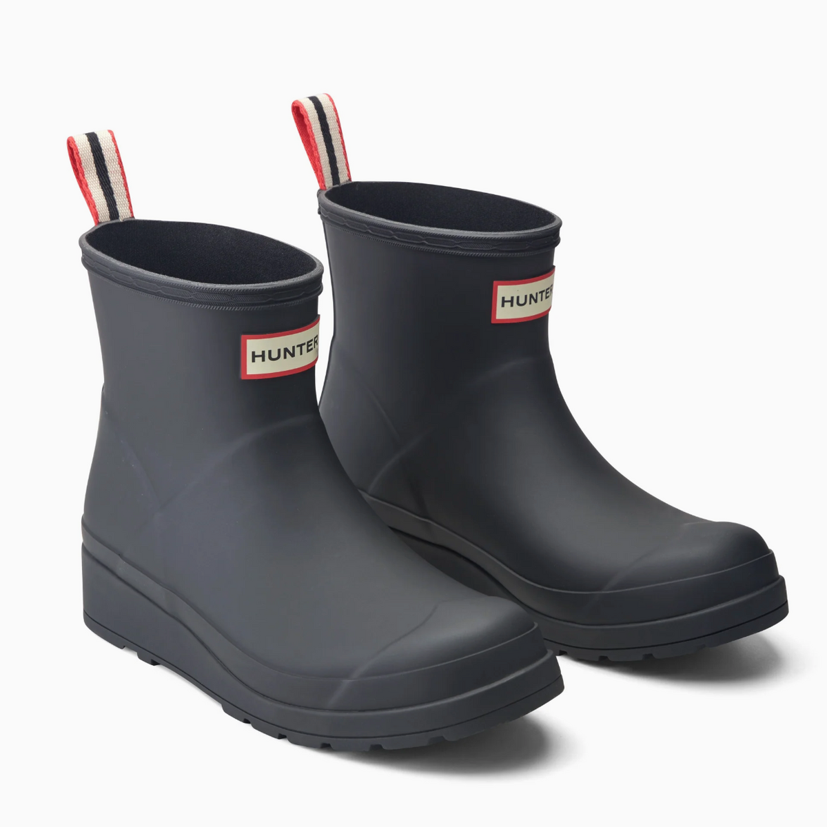 A pair of Hunter rain boots in dark charcoal gray, featuring the brand's signature red, white, and black striped pull tabs and a small Hunter logo patch on the side, set against a clean white background.